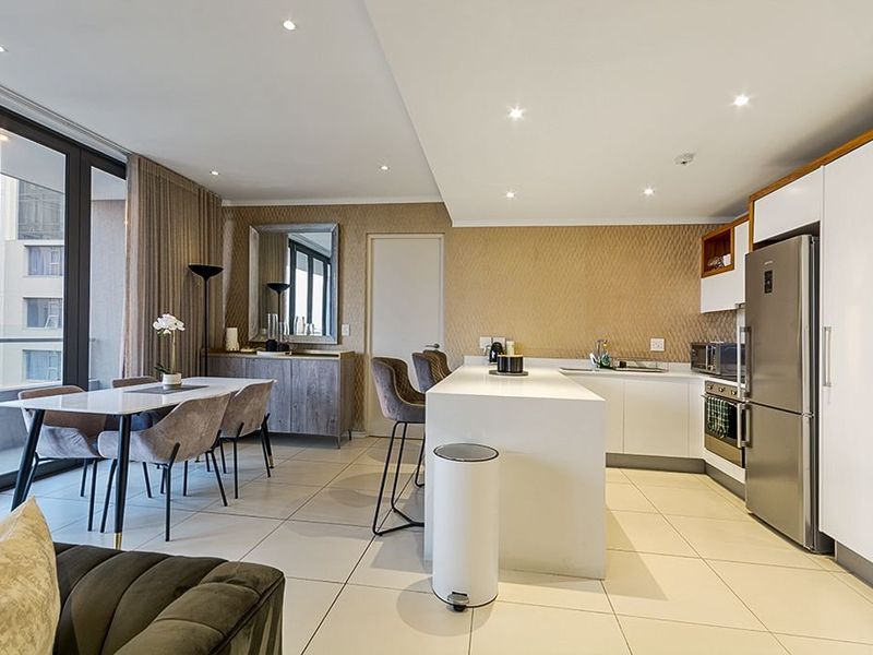 Modern open-plan living area featuring a sleek kitchen with a central island, built-in appliances, and large sliding doors leading to an outdoor space.