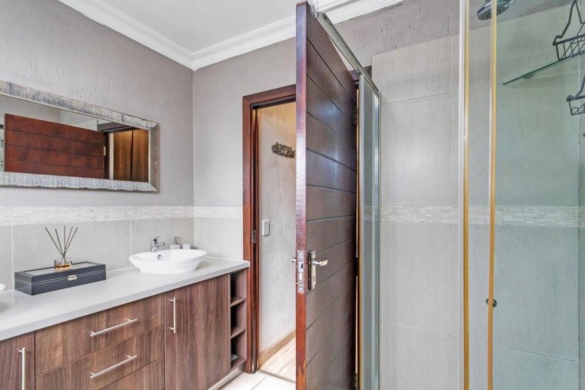 Modern bathroom featuring a vanity cabinet with a countertop basin, tiled walls, and a glass-enclosed shower.