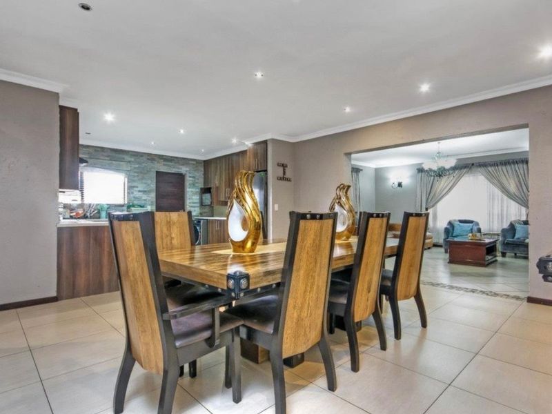 Spacious open-plan dining and kitchen area featuring modern cabinetry, stone-cladding accents, and recessed lighting, seamlessly flowing into the adjacent living space.