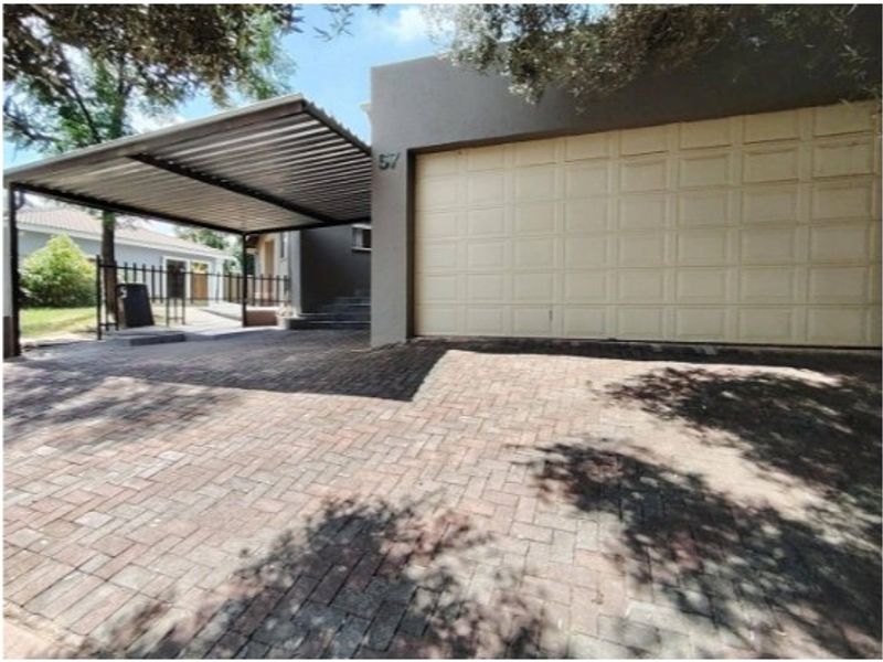 Front exterior view featuring a paved driveway, a covered carport, and a single garage door entrance.