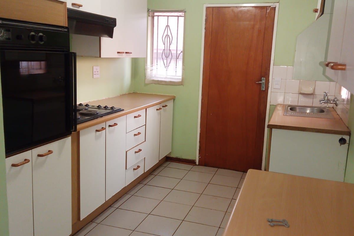 A functional kitchen featuring built-in cabinetry, a gas hob, an integrated oven, and tiled flooring, offering a practical layout for renovation.