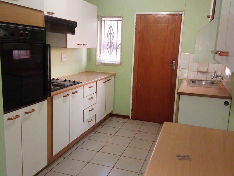 A functional kitchen featuring built-in cabinetry, a gas hob, an integrated oven, and tiled flooring, offering a practical layout for renovation.