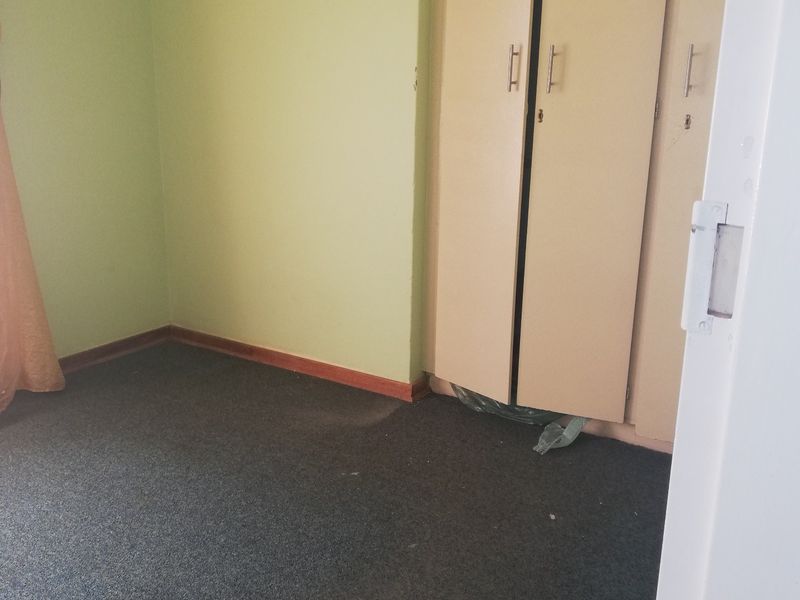 A vacant bedroom featuring built-in cupboards and carpeted flooring, presenting a blank canvas for potential updates and interior design improvements.