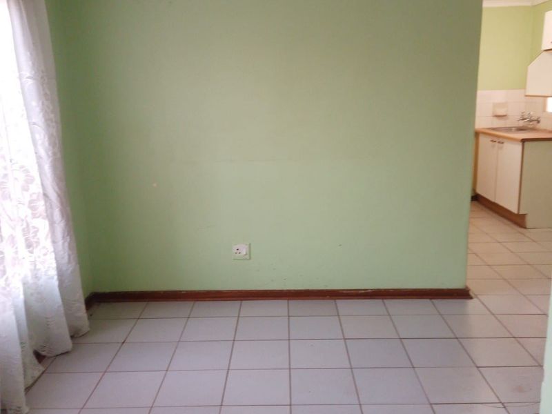 An empty open-plan living area featuring tiled floors and a view into the adjacent kitchen space.