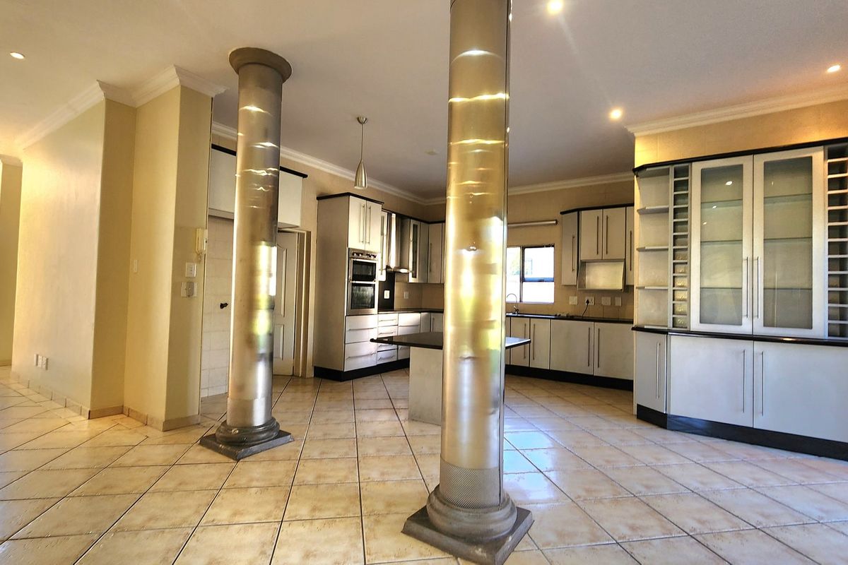 Spacious kitchen featuring built-in cabinetry, integrated oven, stone countertops, and distinctive decorative columns, set on tiled flooring with recessed lighting.