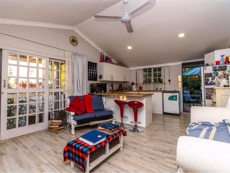 Open-plan living area featuring a kitchen with island, ceiling fan, recessed lighting, and sliding glass doors leading to an outdoor space.