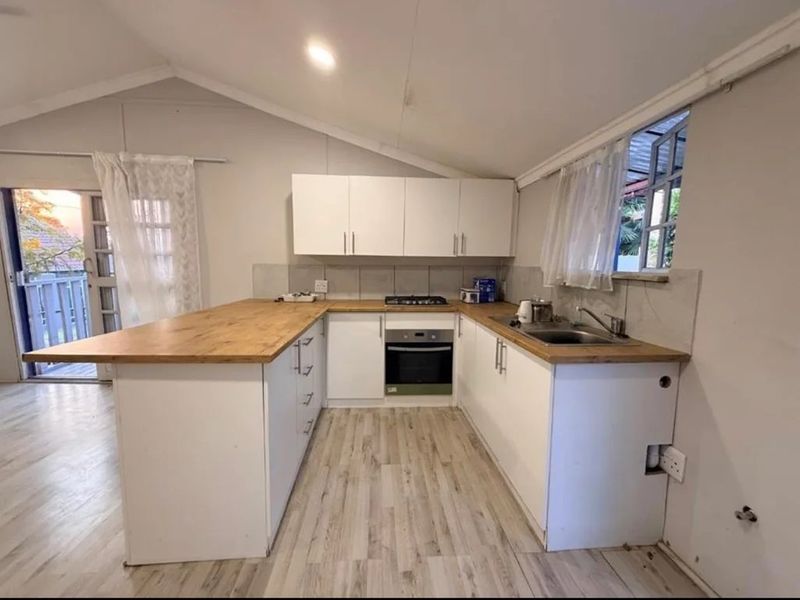 A functional kitchen featuring white cabinetry, wooden countertops, a built-in oven, and a gas hob, with direct access to an outdoor balcony area.