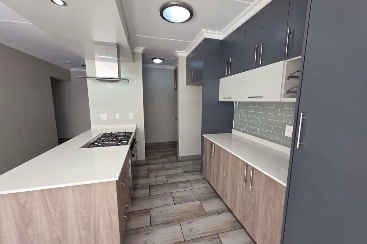 Modern kitchen featuring two-tone cabinetry, quartz countertops, subway tile backsplash, gas hob with extractor fan, and durable laminate flooring.