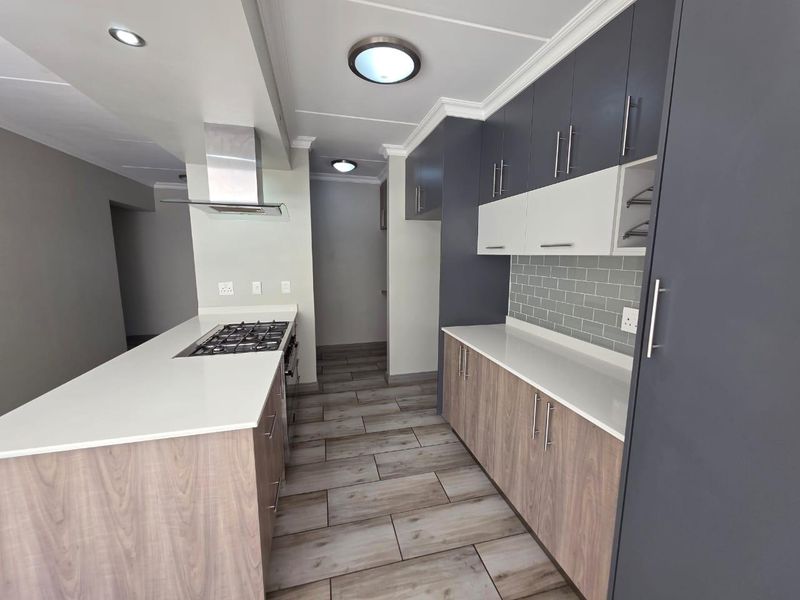 Modern kitchen featuring two-tone cabinetry, quartz countertops, subway tile backsplash, gas hob with extractor fan, and durable laminate flooring.