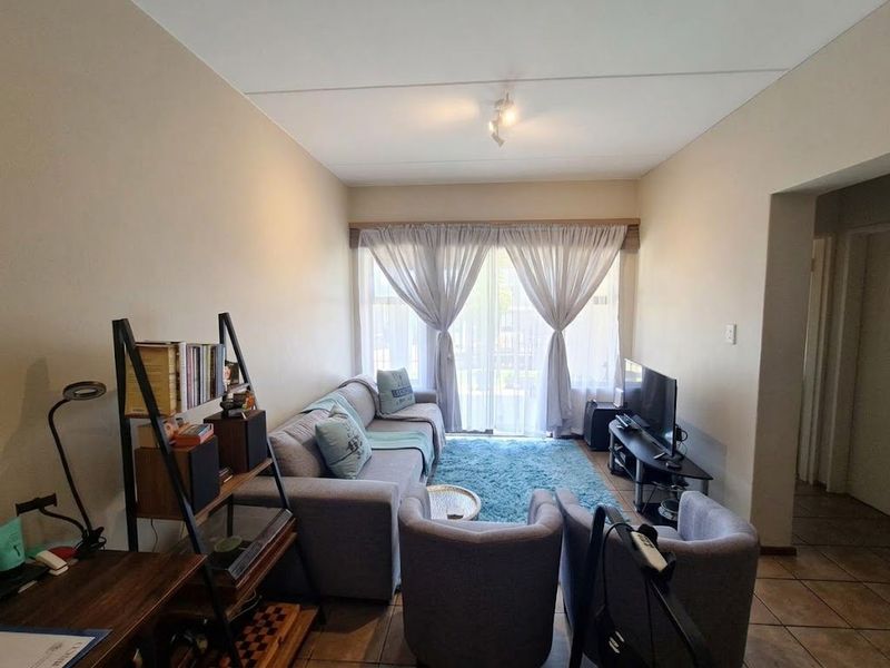 A comfortable living room featuring tiled flooring and a large sliding glass door that provides natural light and access to the outdoor area.