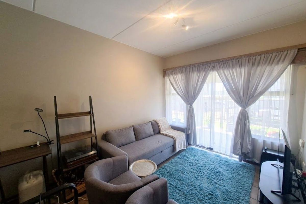 A comfortable living room featuring tiled flooring and a large sliding glass door that provides natural light and access to the exterior.