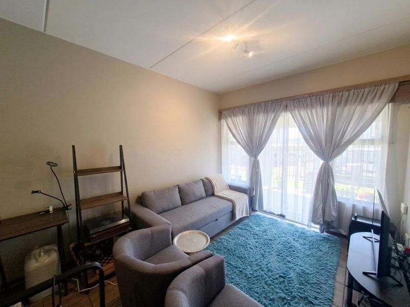 A comfortable living room featuring tiled flooring and a large sliding glass door that provides natural light and access to the exterior.