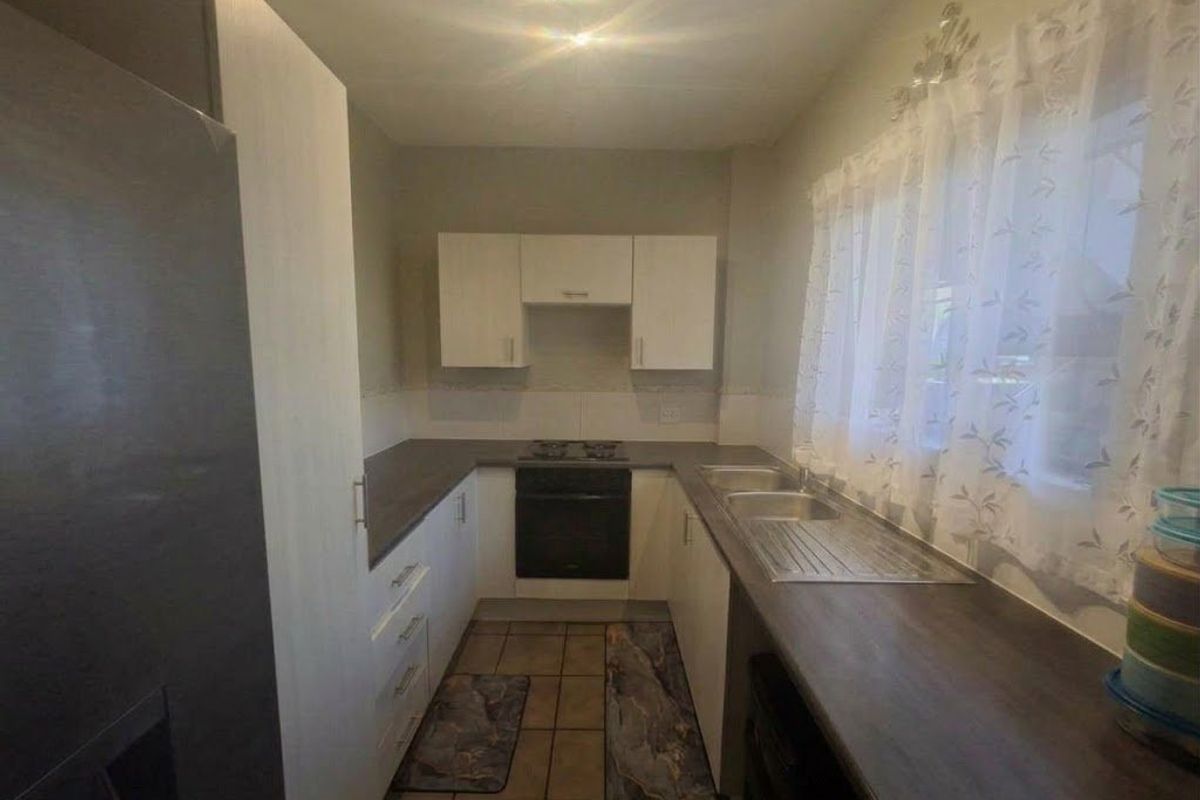 A functional kitchen featuring built-in cabinetry, laminate countertops, a stainless steel double sink, and a built-in oven with an electric hob.