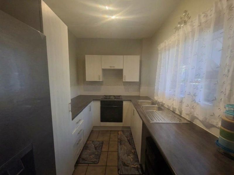 A functional kitchen featuring built-in cabinetry, laminate countertops, a stainless steel double sink, and a built-in oven with an electric hob.