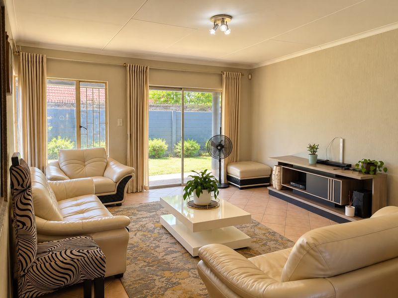 A bright and spacious living room featuring tiled floors, neutral walls, and large sliding glass doors that provide direct access to the rear garden.