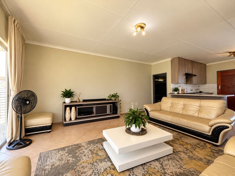 Open plan living area featuring tiled floors, neutral walls, and an integrated kitchen with cabinetry and built-in appliances.