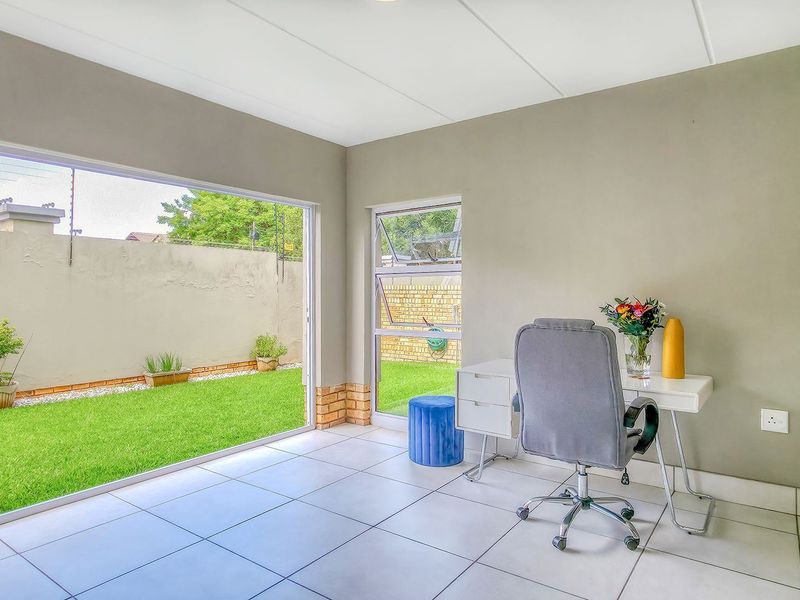 A bright home office featuring large sliding glass doors that provide direct access to the garden and ample natural light.