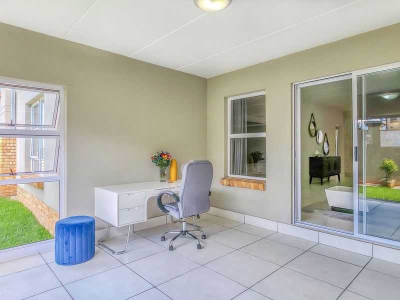 A bright, enclosed patio area featuring large sliding glass doors, tiled flooring, and views of the surrounding garden space.