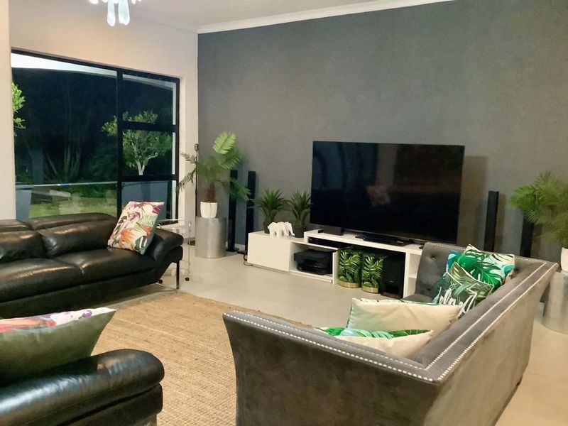 A spacious living room featuring large sliding glass doors, neutral tiled flooring, and a dark grey accent wall.