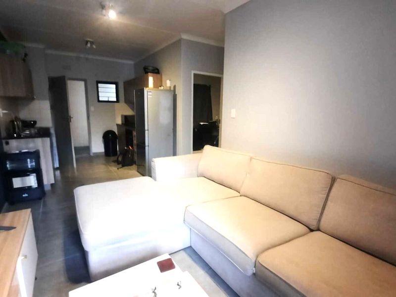 Open plan living area featuring tiled flooring and an integrated kitchen space with cabinetry.
