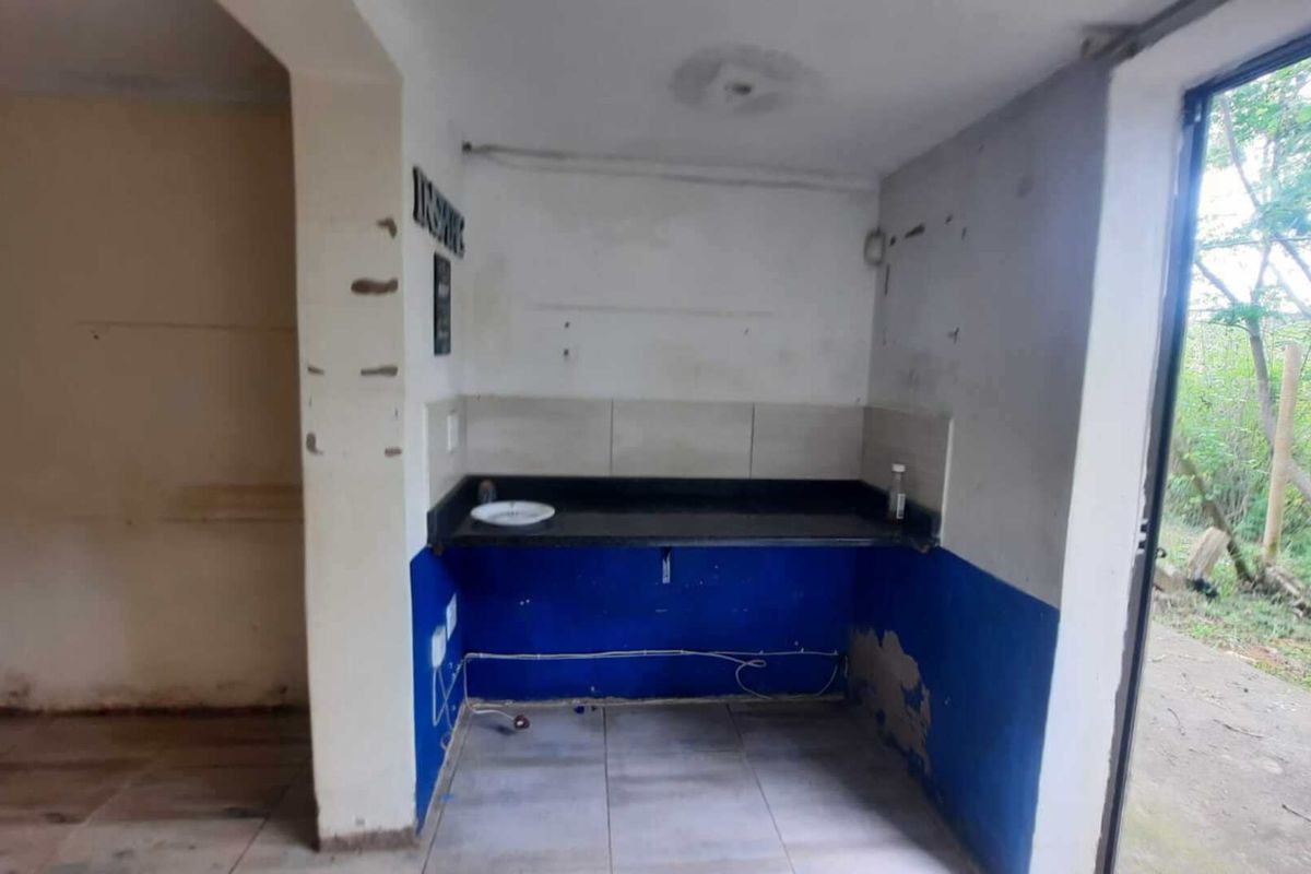 A small, empty kitchen area featuring a granite countertop, tiled splashback, and direct access to the outdoors via a sliding glass door.