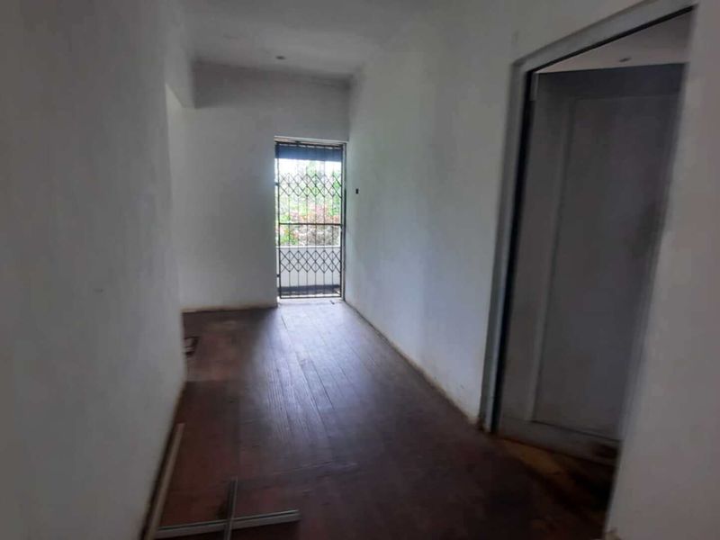 An empty hallway featuring laminate flooring and a security gate, currently in need of minor cosmetic repairs and finishing touches.