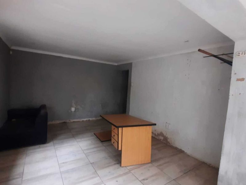 A living area featuring tiled flooring and cove cornicing, currently requiring wall repairs and repainting to improve the overall condition of the space.