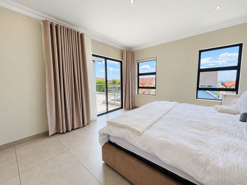 Spacious bedroom featuring neutral tiled flooring, recessed lighting, and a sliding glass door providing direct access to an outdoor balcony area.