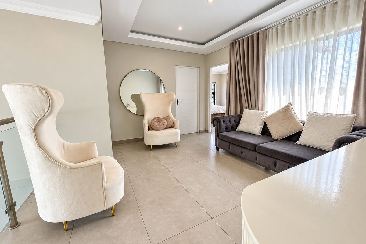 A bright and modern living room featuring neutral tiled flooring, a recessed ceiling with integrated lighting, and large windows with floor-to-ceiling curtains.