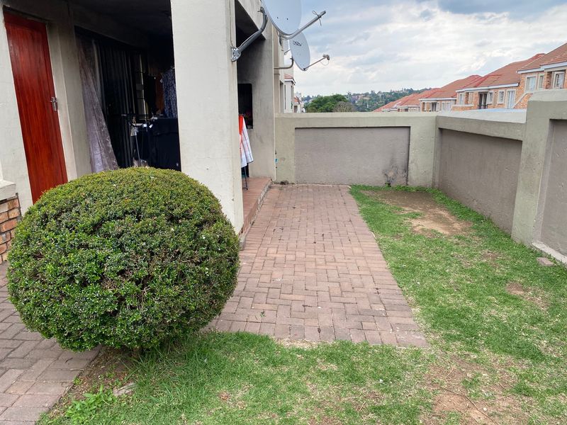 A private paved patio area with a boundary wall and small garden space, offering potential for outdoor seating and landscaping improvements.