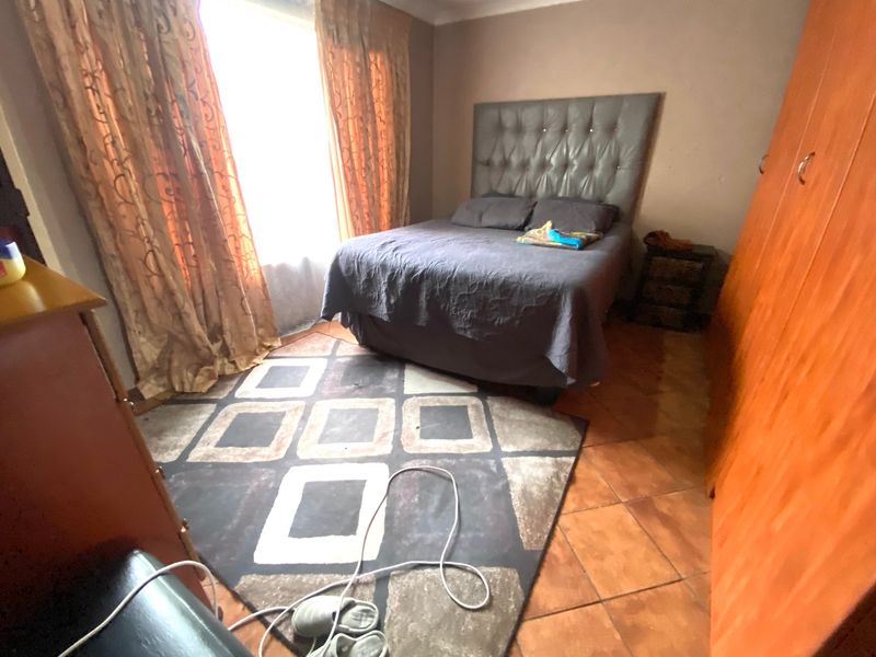 A bedroom featuring tiled flooring and a built-in wardrobe, offering a functional space with natural light from the window.