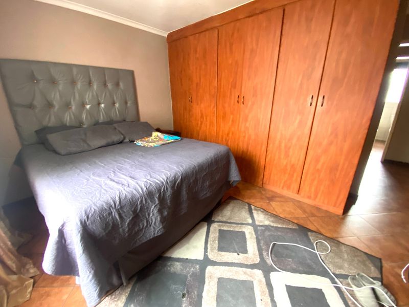 A bedroom featuring built-in wooden wardrobes and tiled flooring, offering functional storage space within the townhouse.