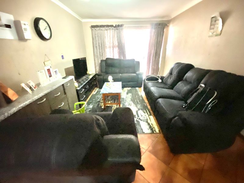 A living room featuring tiled flooring and cove cornicing, currently showing signs of wear on the wall surfaces.