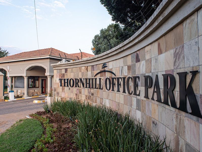 Entrance view of Thornhill Office Park featuring a stone-clad boundary wall, security gatehouse, and well-maintained landscaping.
