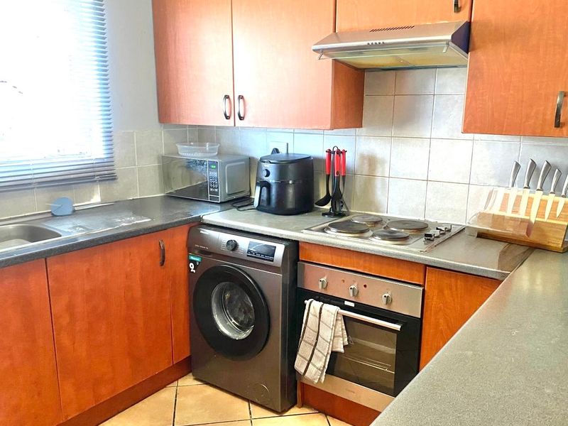 Functional kitchen featuring laminate cabinetry, built-in oven with electric hob, extractor fan, and tiled backsplash, offering a practical layout for daily meal preparation.