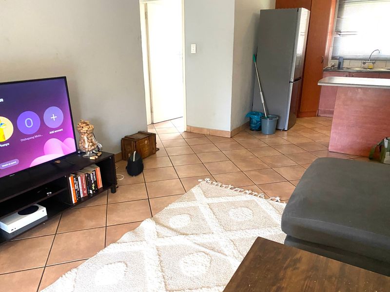 Open plan living area featuring tiled flooring and a functional kitchen space with built-in cabinetry and countertops.