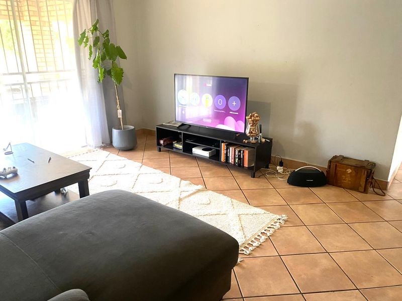 A living room area featuring tiled flooring and a sliding glass door providing natural light.