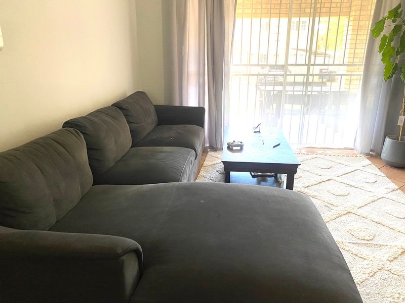 A living room area featuring tiled flooring and a sliding glass door with an integrated security gate, providing access to the outdoor space.