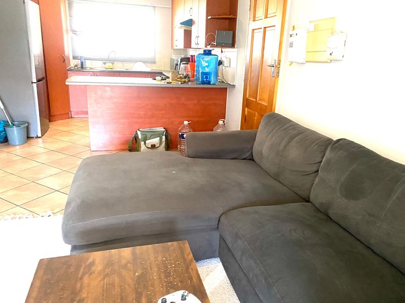 Open plan living area featuring a kitchen with breakfast bar and tiled flooring, seamlessly connected to the lounge space.