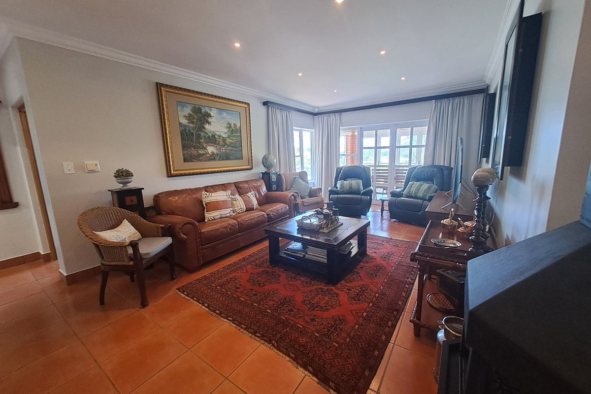 A comfortable living room featuring terracotta floor tiles, recessed downlighting, and direct access to an outdoor area through glass-paned french doors.