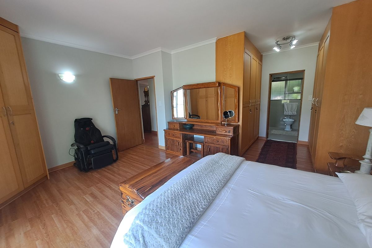 Spacious bedroom featuring extensive built-in wooden cabinetry, laminate flooring, and direct access to an en-suite bathroom.