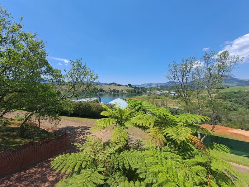A scenic elevated view overlooking a lake, surrounding hills, and landscaped grounds, showcasing the property's natural setting and landscape.
