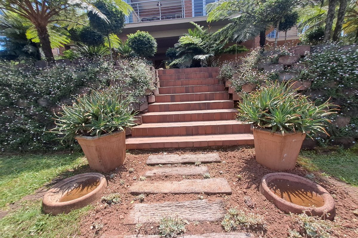 A landscaped rear garden featuring a brick staircase leading up to a balcony with metal railings.
