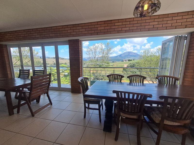 Spacious covered patio featuring exposed brick walls, tiled flooring, and large bi-fold glass doors that open to scenic mountain and landscape views.