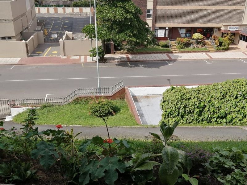 An elevated view overlooking a quiet street, paved parking area, and surrounding neighborhood greenery.