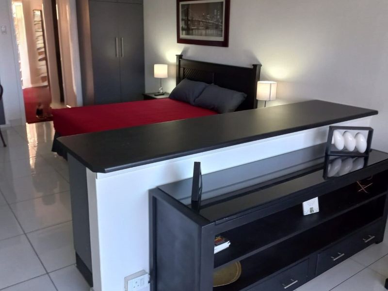 Open plan living and bedroom area featuring tiled flooring and built-in storage cupboards, providing a functional layout for apartment living.
