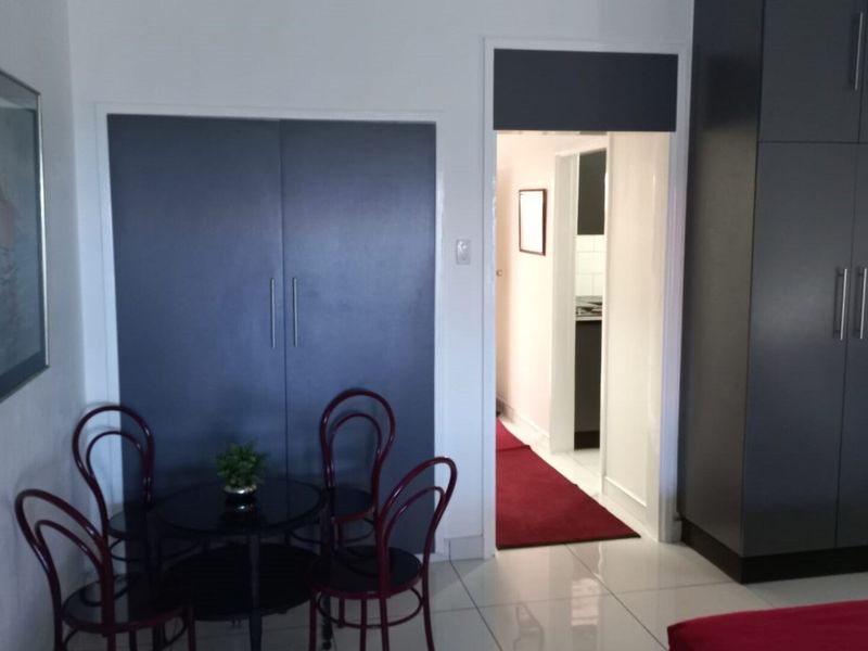 Bedroom featuring modern dark grey built-in cupboards, tiled flooring, and a doorway leading to an adjacent space.