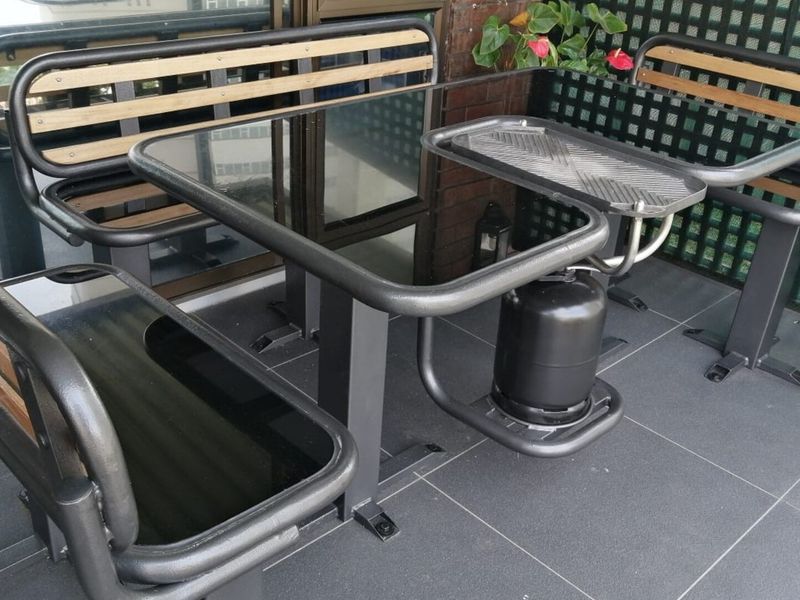 A private balcony featuring dark tiled flooring, a brick feature wall, and a privacy lattice screen.