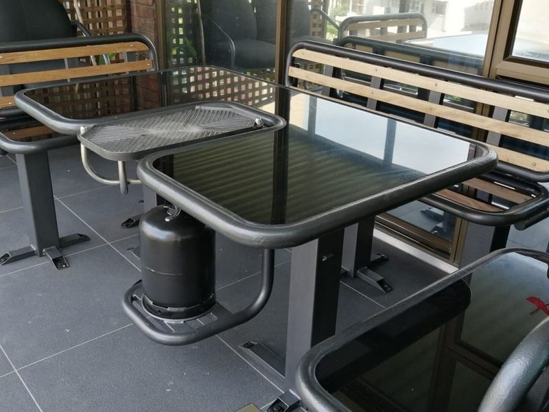 A covered balcony area featuring dark tiled flooring and large sliding glass doors, providing a functional outdoor space.