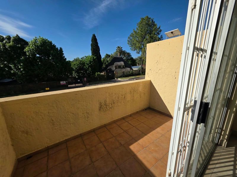 A compact balcony featuring tiled flooring and a security gate, offering an outdoor space with potential for enhancement.